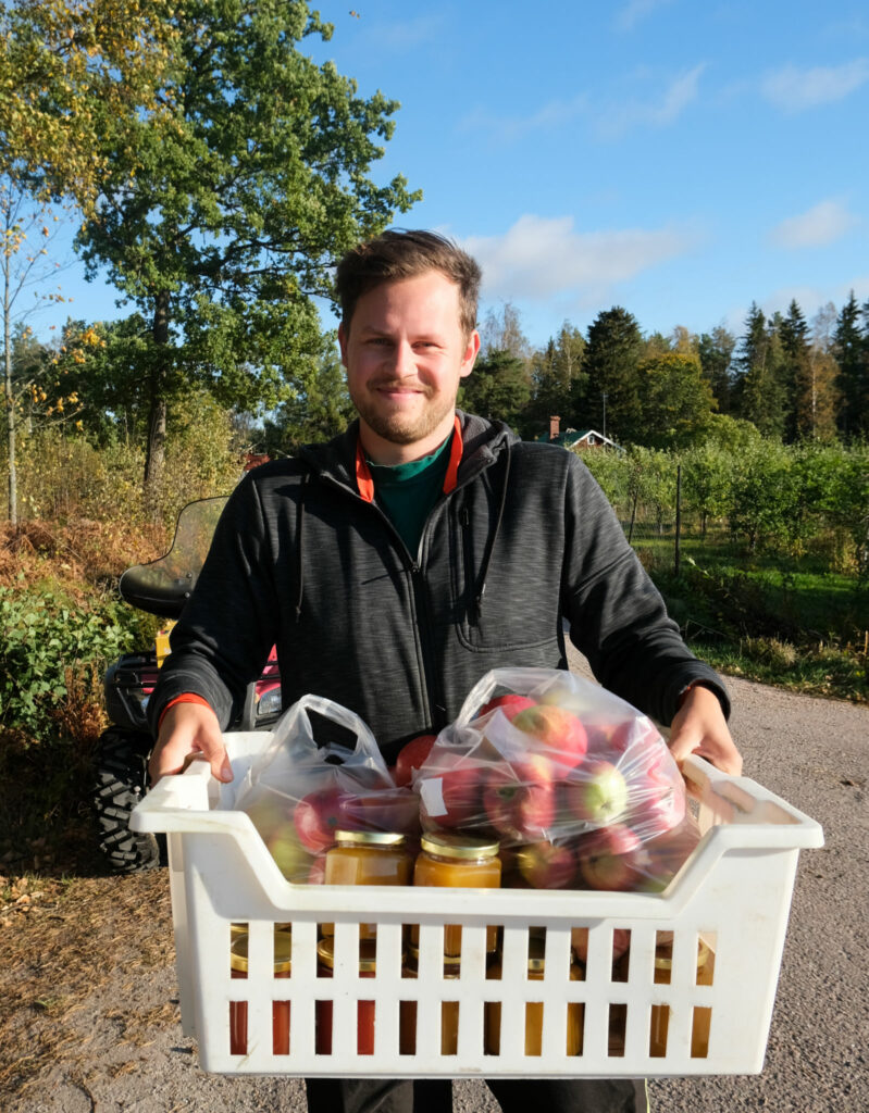 Mikael Hämäläinen med en låda äpplen i famnen.