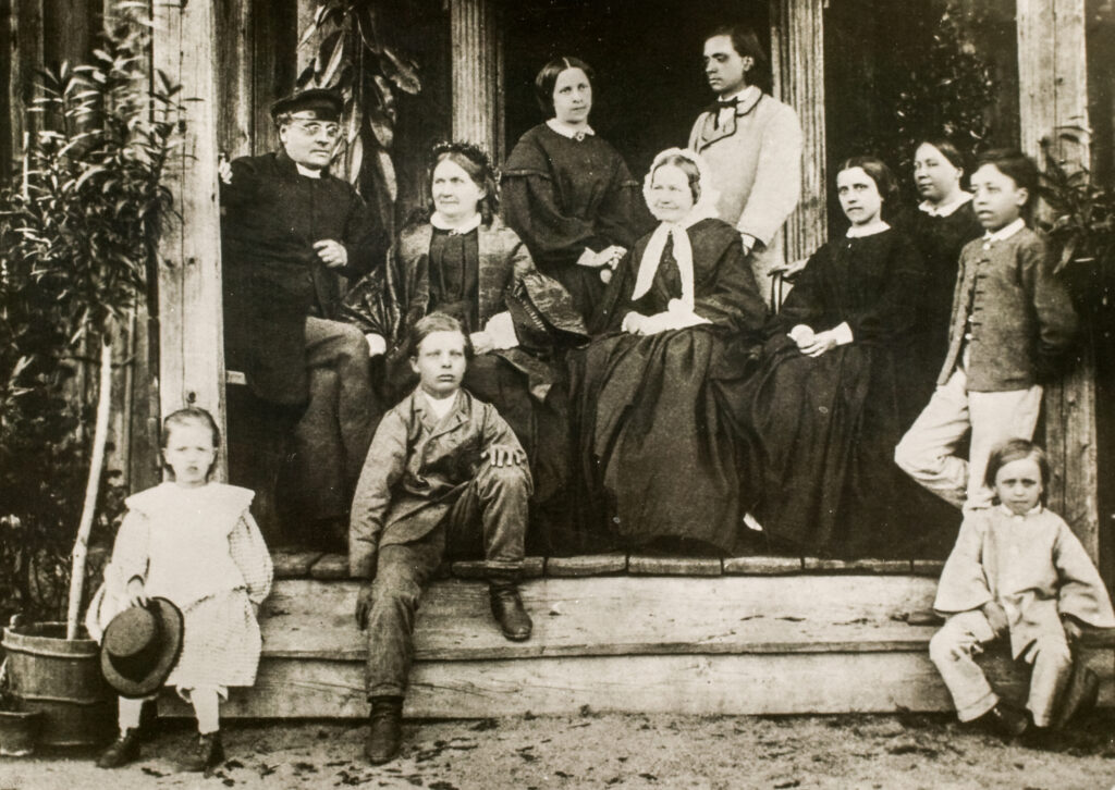 Gammal svartvit bild av en familj på en veranda.