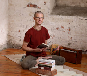 Janne Kontala sitter på en yogamatta med en bok i handen.