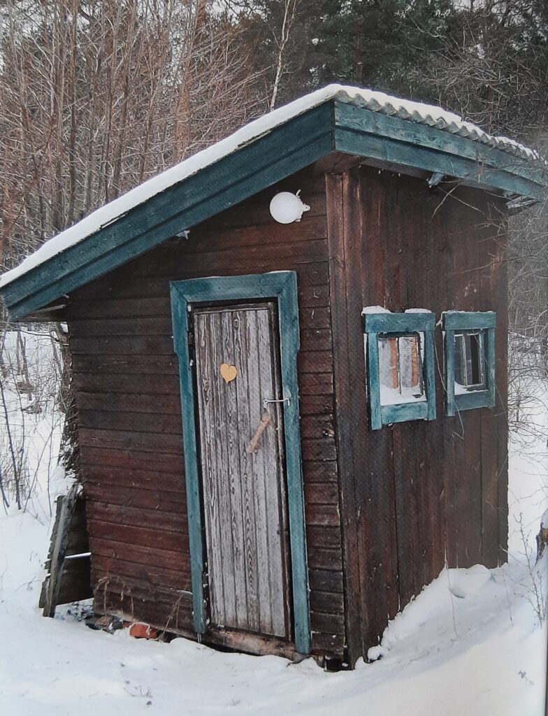 En liten träd byggnad i snön.