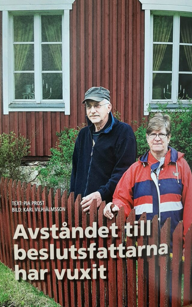 Sida i en tidning med ett par bakom rött staket och framför ett rött trädhus.