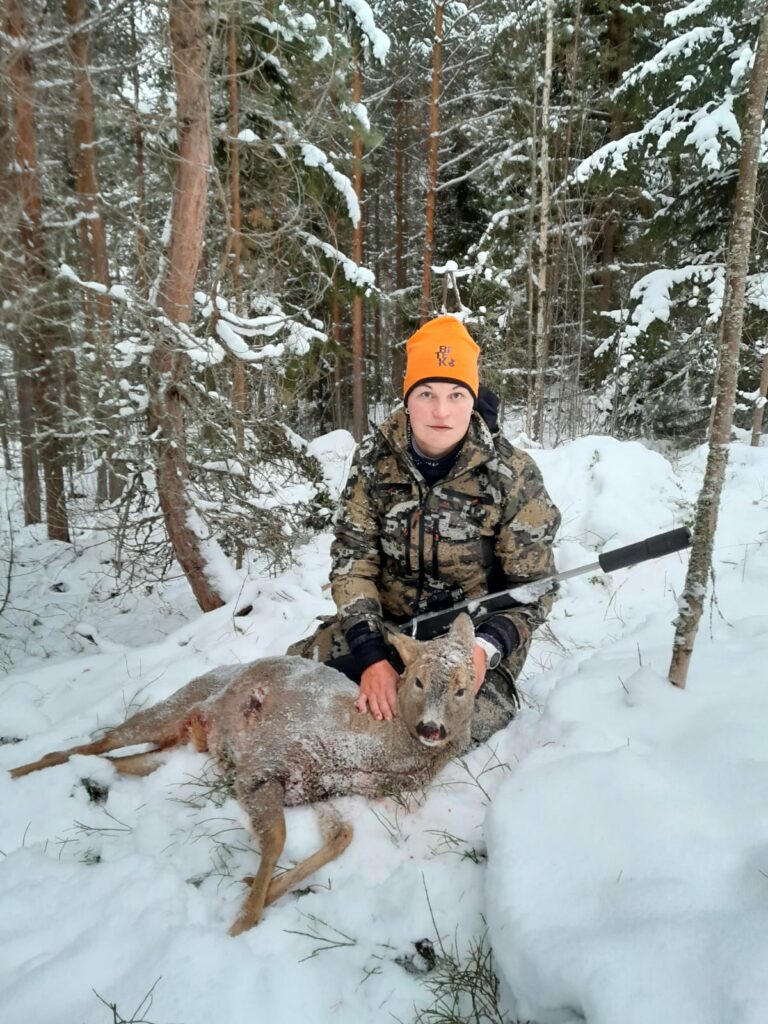 Lilja Järvinen i jaktkläder vid ett fällt rådjur.